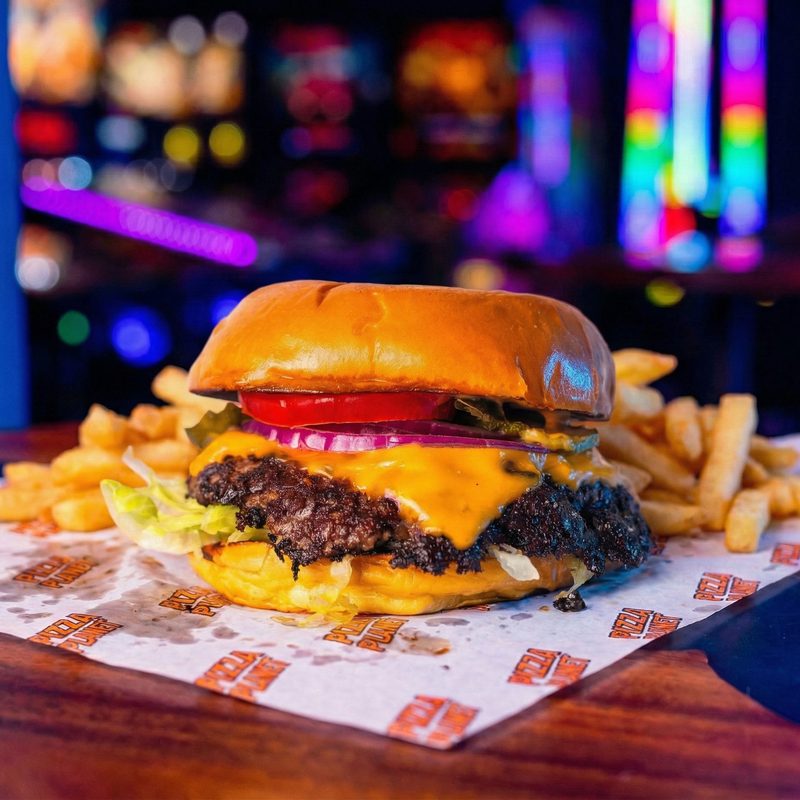 The Oklahoma - smashed beef burger with crispy charred onion crust, American cheese, tomato, red onion and pickles on a brioche bun.
