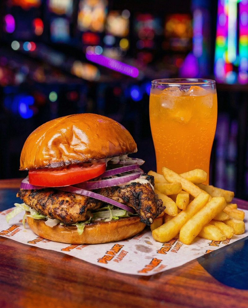 Jerk Chicken lunch deal - flame-grilled jerk chicken with red onion and tomato, served with chips and an orange drink.