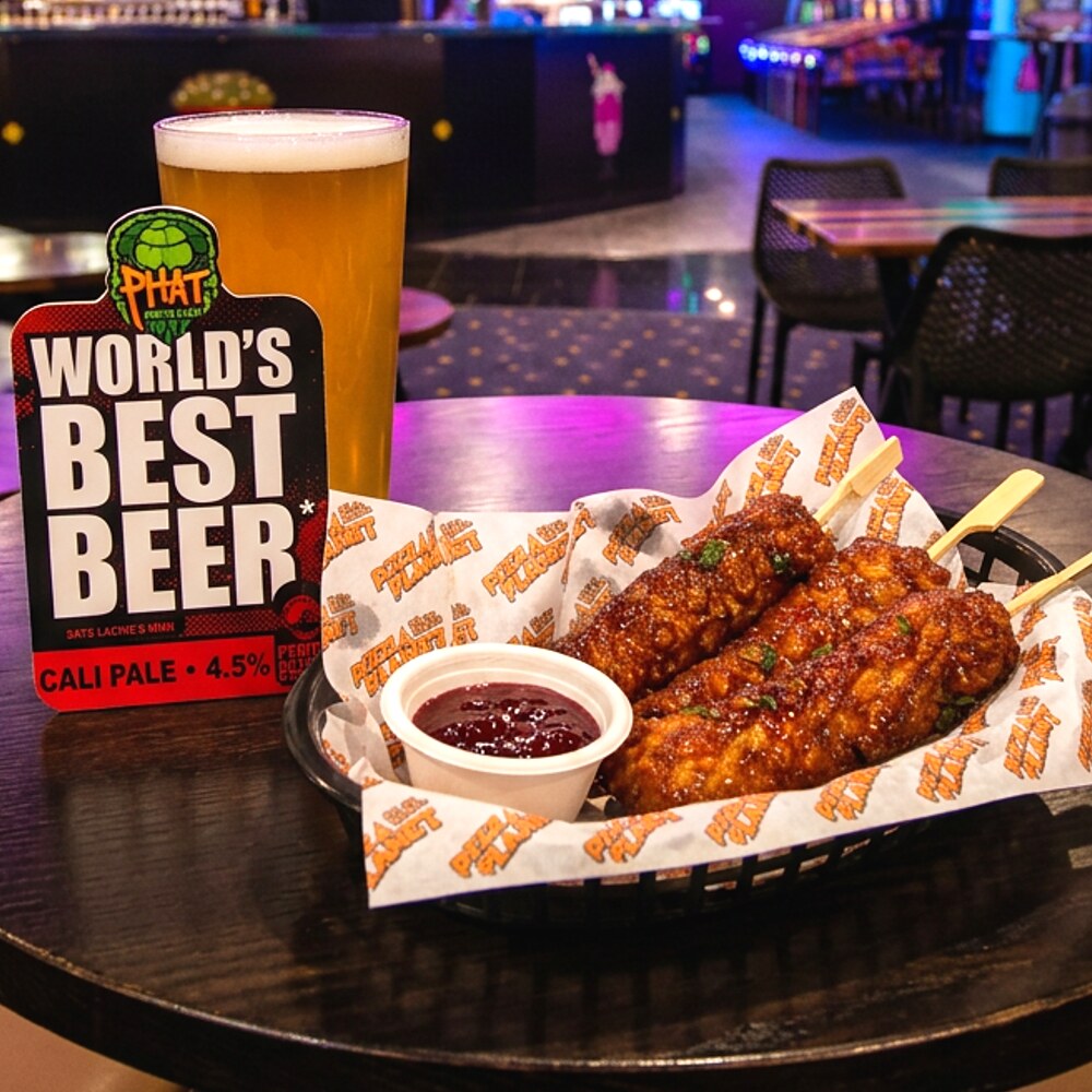 Three deep fried halloumi sticks glazed with hot honey, served with a pot of cranberry jam on a dark table at Planet Royale.