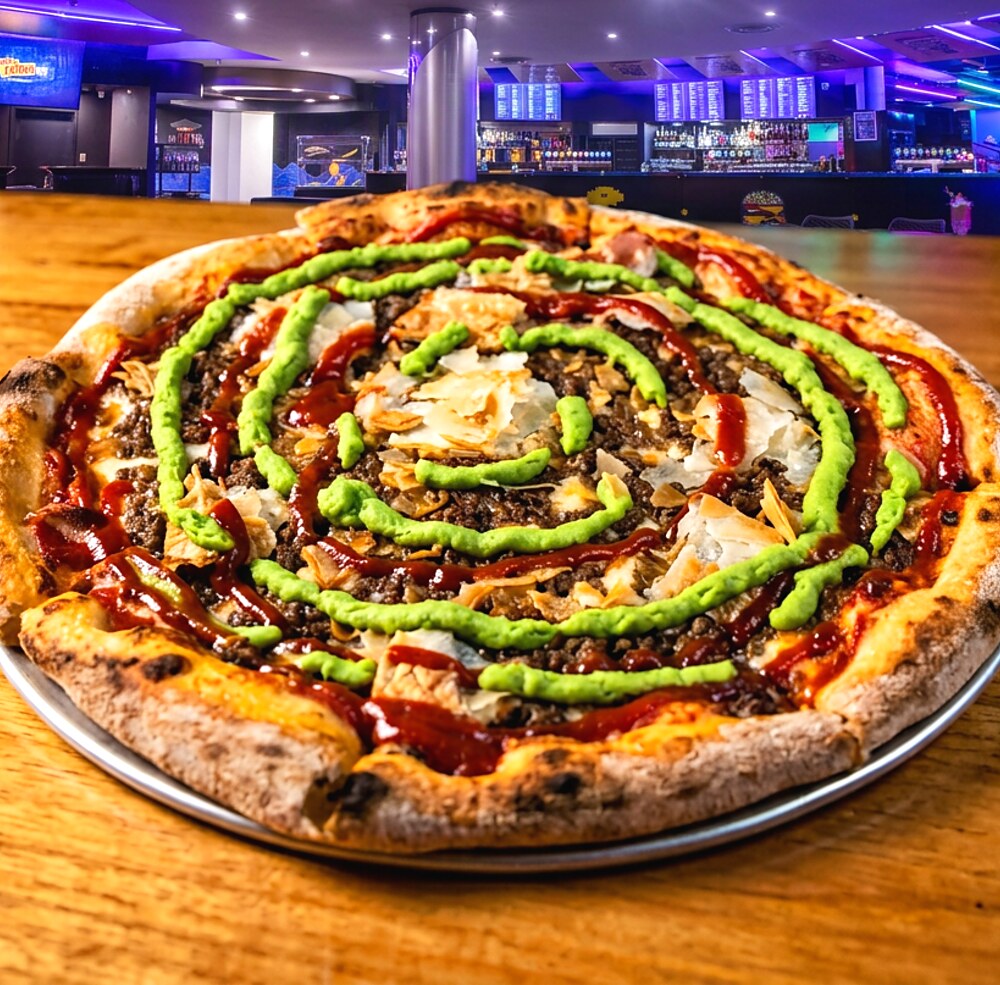 The Servo Meat Pie Pizza, a whole pizza with concentric rings of mushy pea puree and tomato sauce over beef mince, topped with crushed puff pastry.